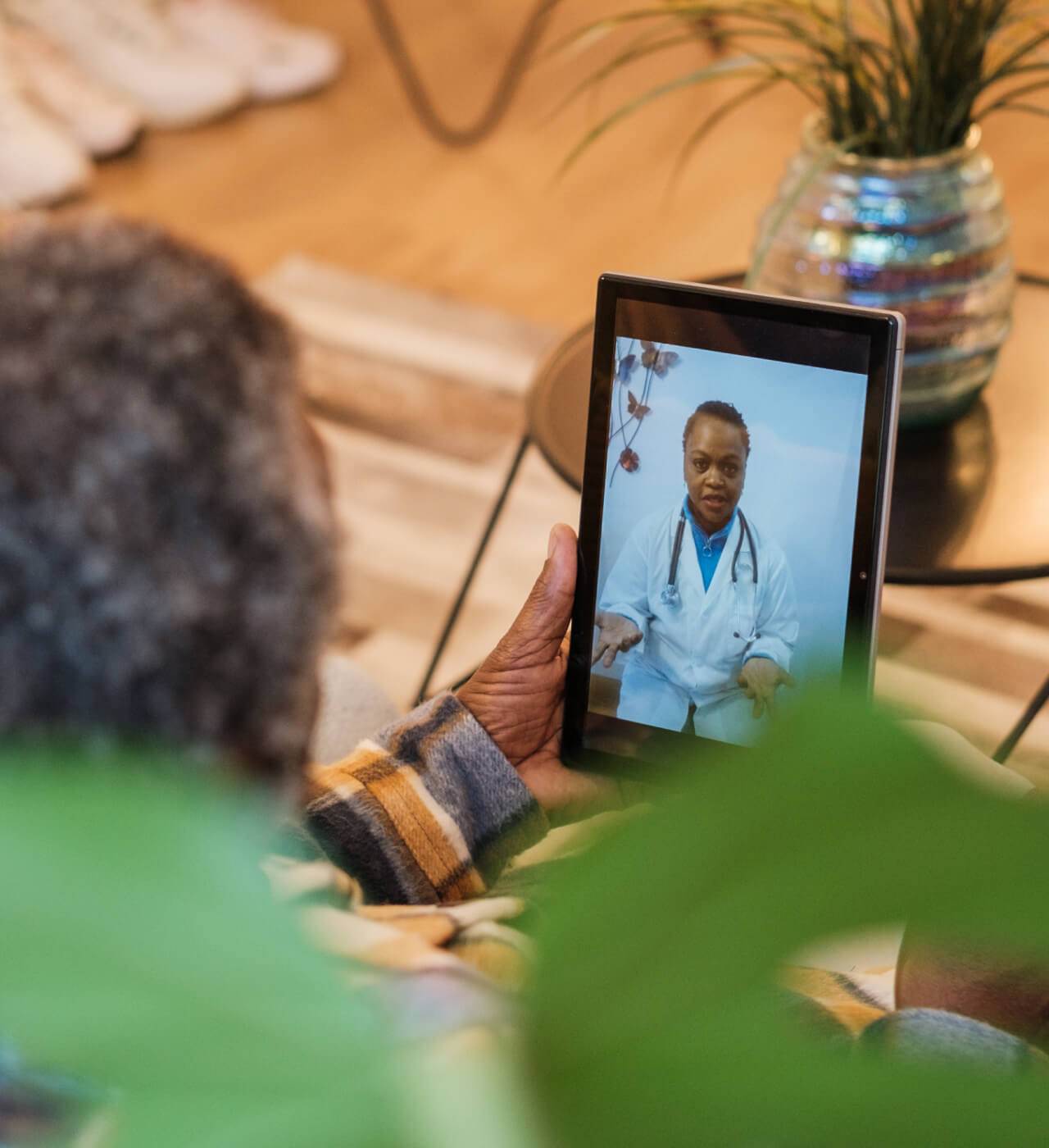 A person is holding a tablet showing a video call with a doctor.